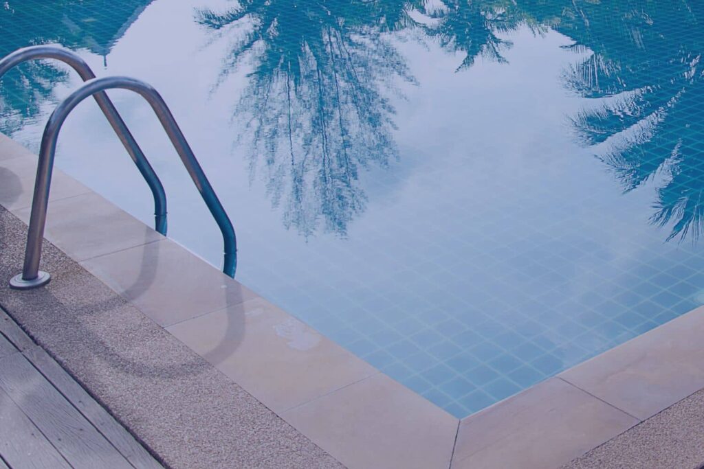 Residential in-ground pool with stainless steel ladder and tile surface being evaluated during a pool inspection in North Carolina
